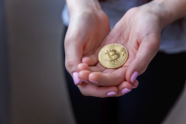 golden bitcoin in a female hand