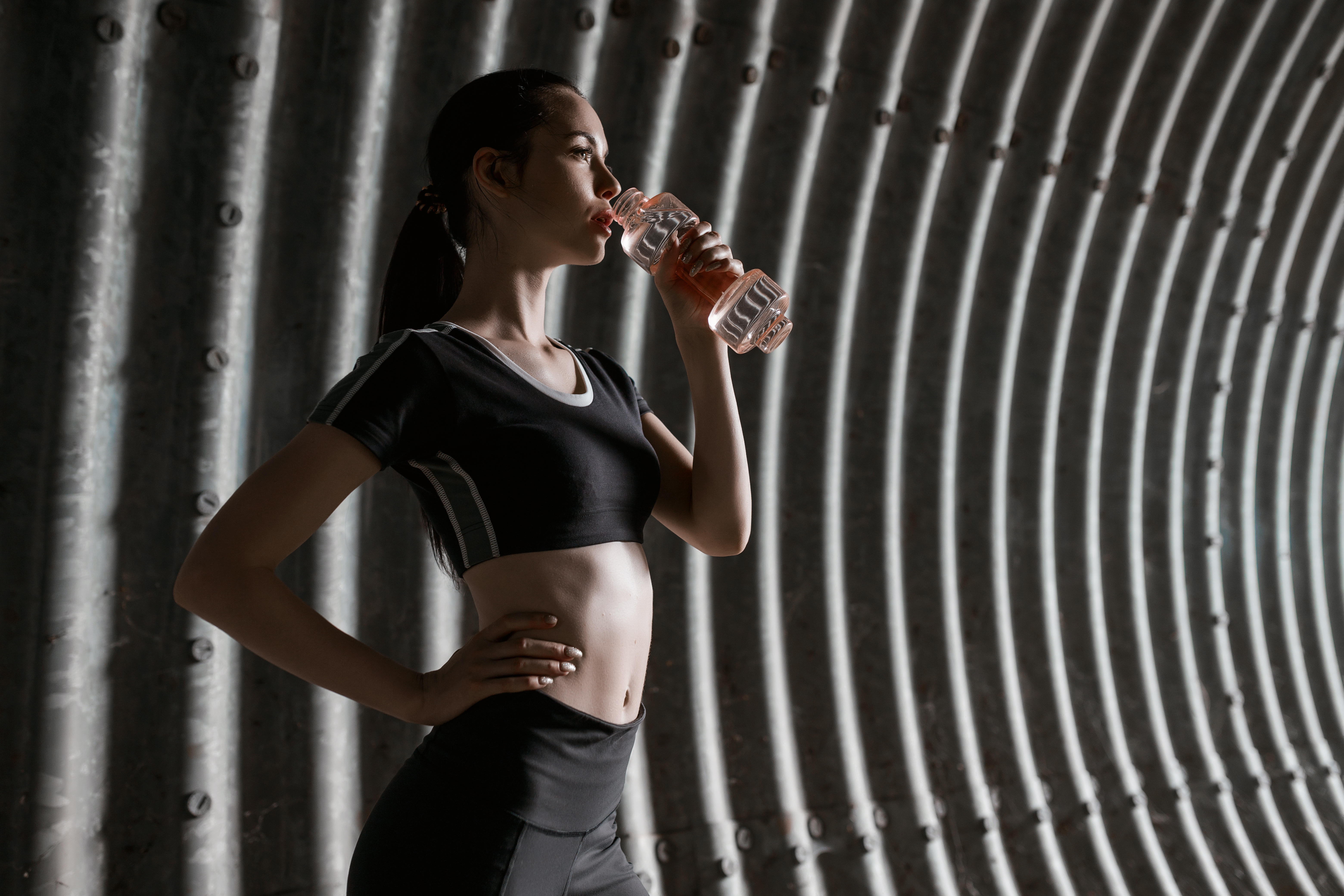 The sportswoman drinks water in the tunnel